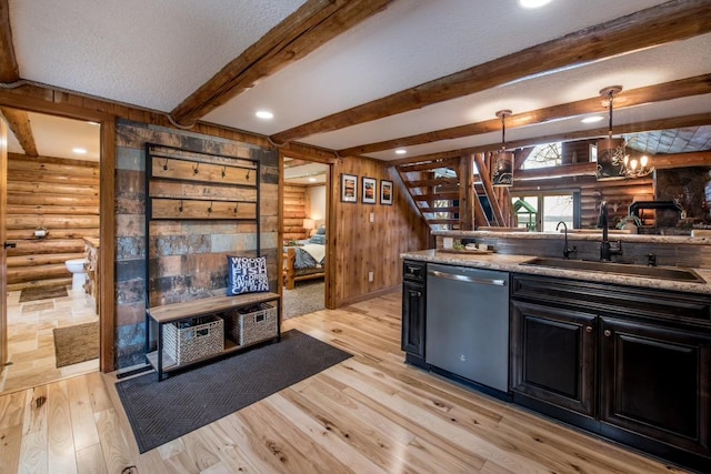 kitchen featuring dark cabinetry, dishwasher, log walls, and a sink