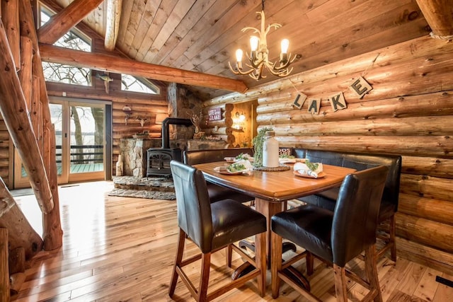 dining space with lofted ceiling with beams, wooden ceiling, hardwood / wood-style flooring, a notable chandelier, and a wood stove