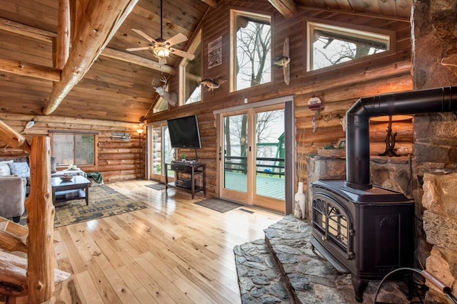 living area featuring beam ceiling, visible vents, wood ceiling, a wood stove, and hardwood / wood-style flooring