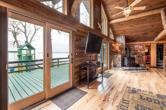 doorway to outside with beam ceiling, wood-type flooring, a wood stove, high vaulted ceiling, and wooden ceiling