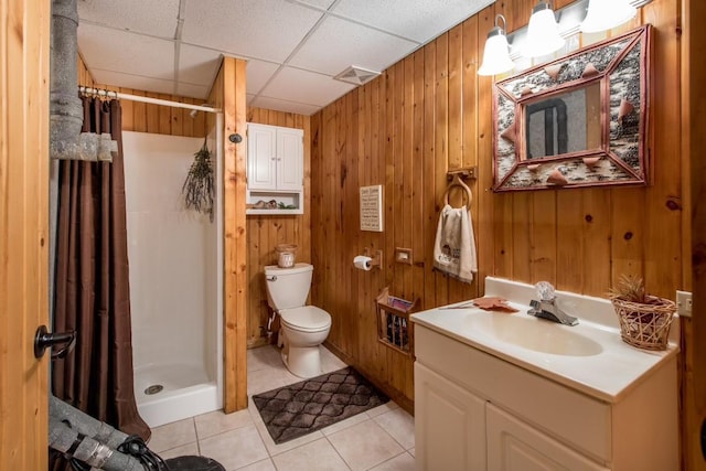 full bath featuring wooden walls, a drop ceiling, toilet, tile patterned flooring, and a shower stall