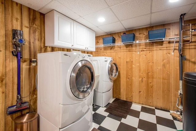 laundry room featuring wooden walls, washer and clothes dryer, cabinet space, and tile patterned floors