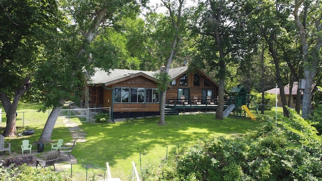 view of yard featuring a deck, a playground, and fence