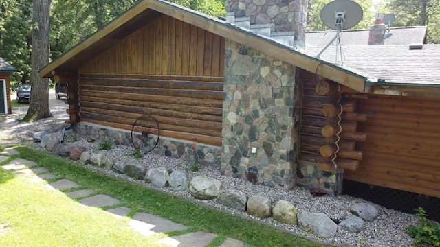 view of side of property featuring log exterior and a chimney