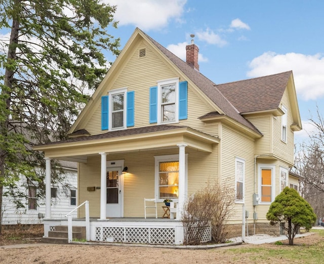 view of front of house with covered porch, a chimney, and a shingled roof