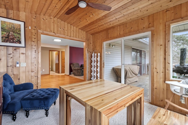 dining space featuring wood finished floors, ceiling fan, vaulted ceiling, wood ceiling, and wood walls