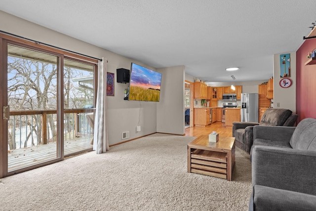 living room with a textured ceiling, baseboards, visible vents, and light carpet