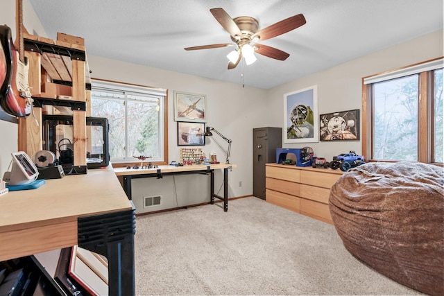 office area featuring visible vents, plenty of natural light, light carpet, and ceiling fan