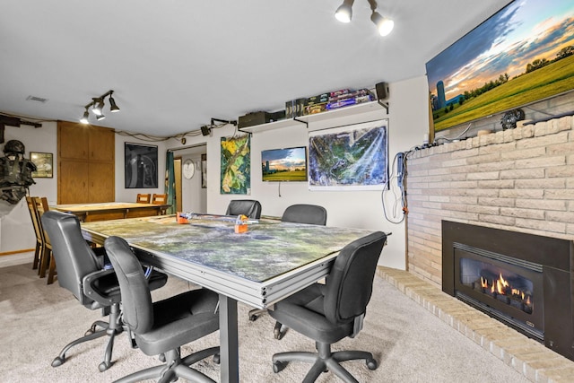 office space featuring light carpet, visible vents, a fireplace, and rail lighting