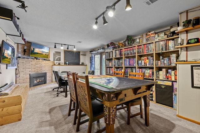 carpeted dining space with visible vents, a textured ceiling, and a brick fireplace