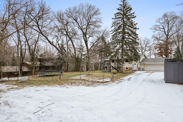 yard covered in snow featuring a trampoline, an attached garage, and a playground