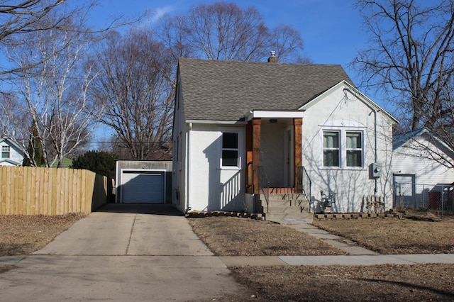 bungalow featuring a shingled roof, fence, concrete driveway, stucco siding, and an outdoor structure