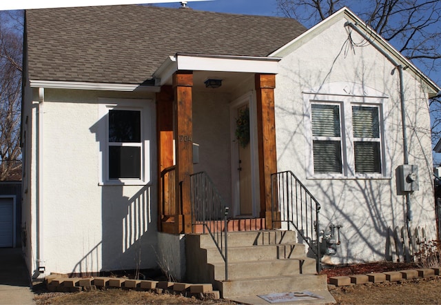 view of front of home featuring roof with shingles and stucco siding