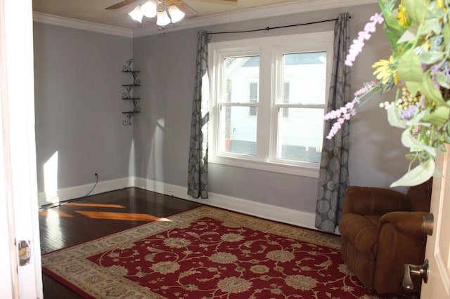 interior space with a ceiling fan, crown molding, baseboards, and wood finished floors