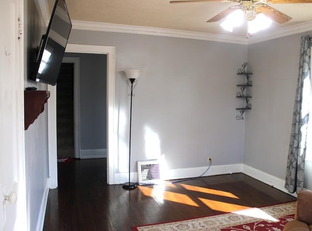 spare room with baseboards, wood finished floors, visible vents, and ornamental molding