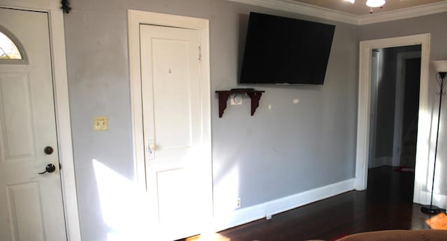 foyer entrance with dark wood-style floors, crown molding, and baseboards