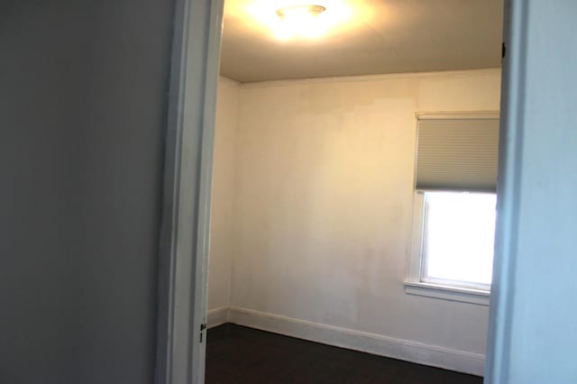 spare room with baseboards and dark wood-style flooring