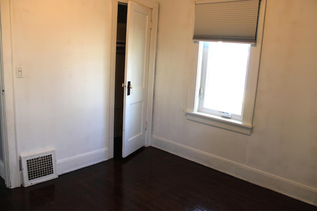 unfurnished bedroom featuring visible vents, baseboards, and dark wood-style flooring