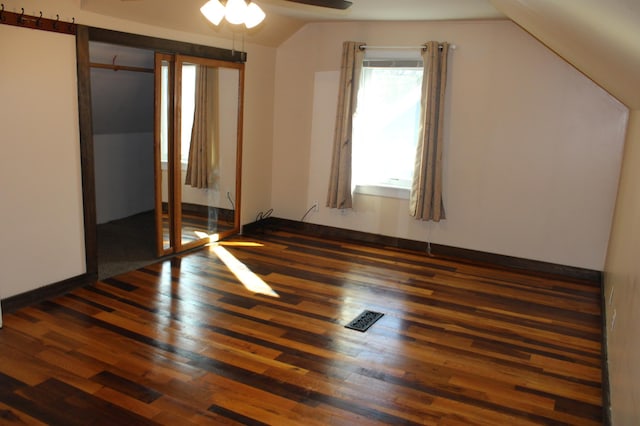 unfurnished bedroom featuring vaulted ceiling, visible vents, and wood finished floors