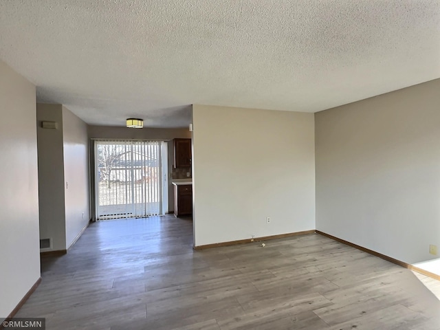 empty room featuring wood finished floors, baseboards, and a textured ceiling