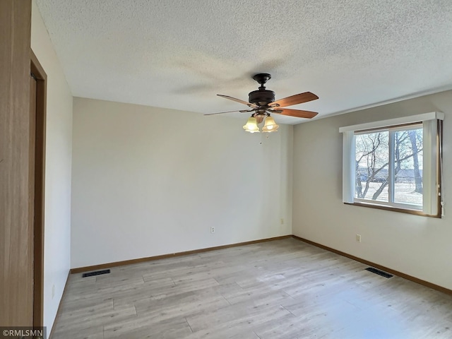 unfurnished room with visible vents, baseboards, light wood-style floors, and a textured ceiling