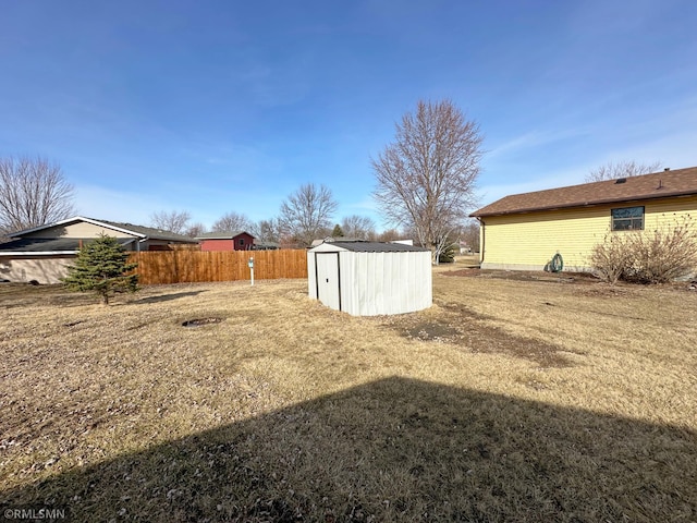 view of yard with an outdoor structure, fence, and a shed