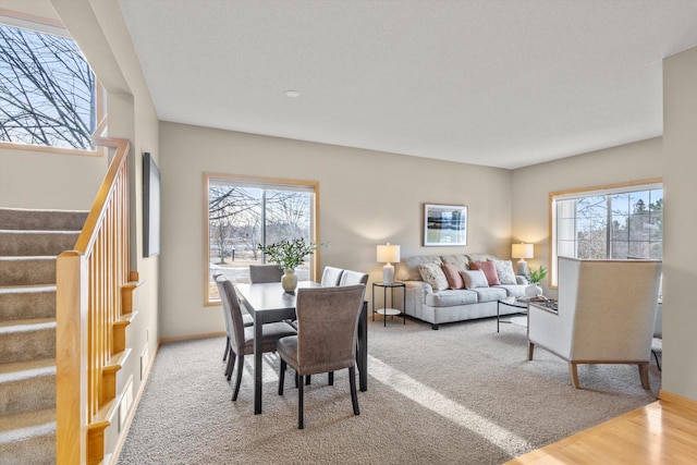 dining room featuring stairs, light wood-style flooring, a healthy amount of sunlight, and baseboards