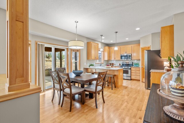 dining room featuring recessed lighting, light wood-style floors, and a textured ceiling