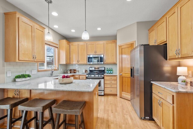 kitchen featuring a peninsula, light brown cabinets, appliances with stainless steel finishes, and a sink