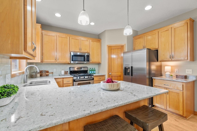 kitchen with light stone counters, a peninsula, stainless steel appliances, and a sink