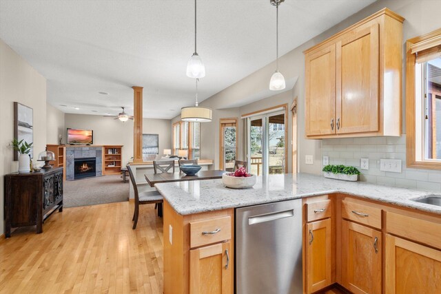 kitchen with light wood-type flooring, tasteful backsplash, stainless steel dishwasher, open floor plan, and a peninsula