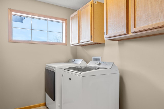 washroom with cabinet space, washer and dryer, and baseboards