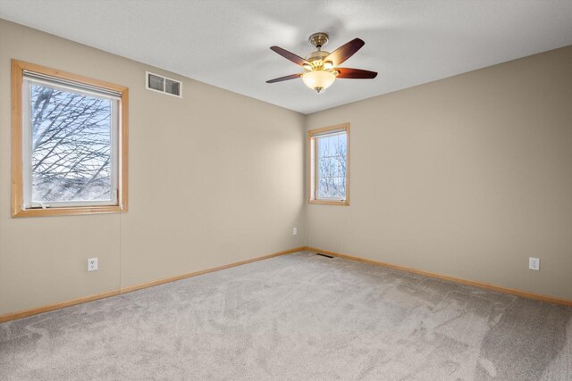 unfurnished room featuring a ceiling fan, carpet flooring, baseboards, and visible vents