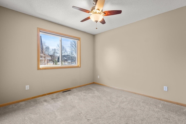 spare room featuring a ceiling fan, baseboards, carpet, visible vents, and a textured ceiling