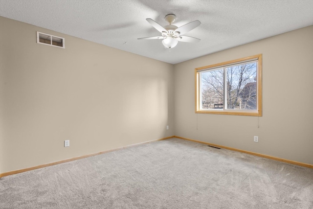 carpeted empty room with baseboards, a ceiling fan, visible vents, and a textured ceiling