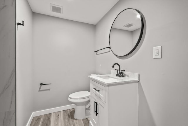 bathroom featuring vanity, wood finished floors, visible vents, baseboards, and toilet