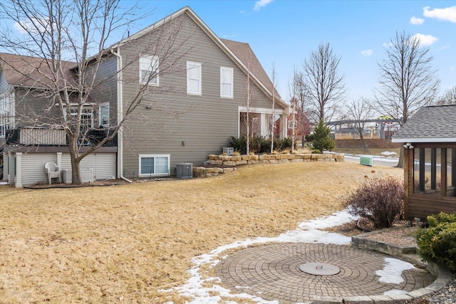 view of property exterior featuring a yard, roof with shingles, and central AC unit