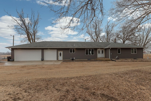 rear view of property featuring roof with shingles, an attached garage, a chimney, and dirt driveway