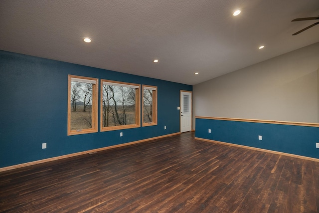 unfurnished room featuring vaulted ceiling, ceiling fan, a textured ceiling, wood finished floors, and baseboards