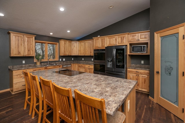 kitchen featuring dark wood finished floors, a kitchen island, vaulted ceiling, black appliances, and recessed lighting