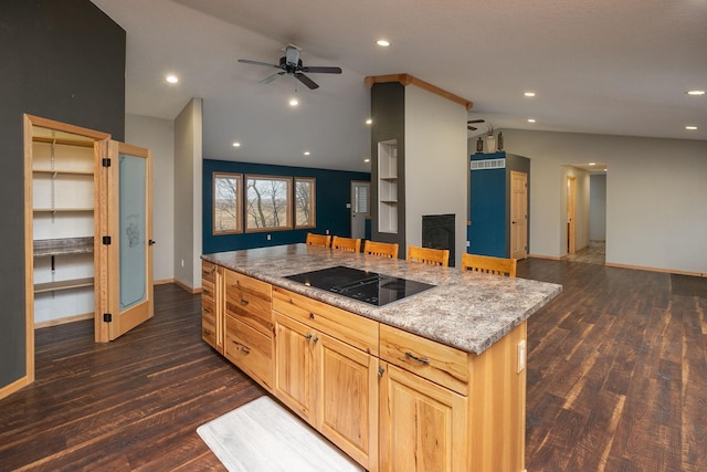 kitchen featuring dark wood-style floors, open floor plan, vaulted ceiling, black electric cooktop, and a fireplace