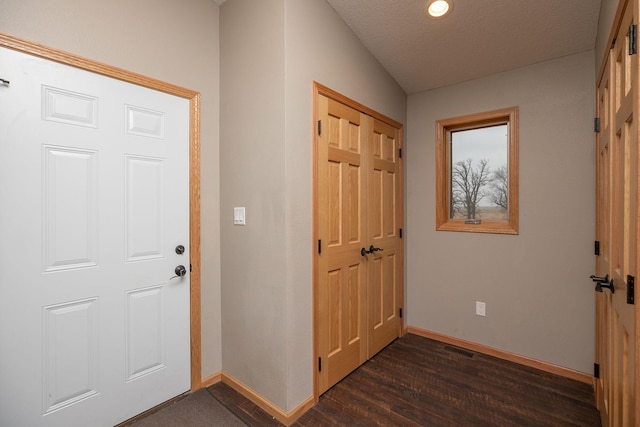 foyer with dark wood finished floors, visible vents, and baseboards