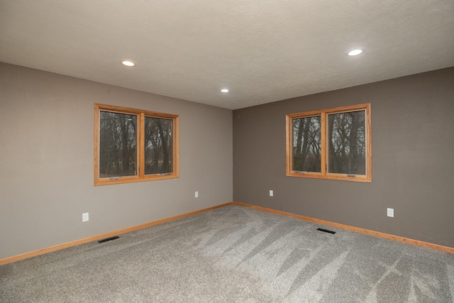 carpeted spare room with recessed lighting, visible vents, a textured ceiling, and baseboards