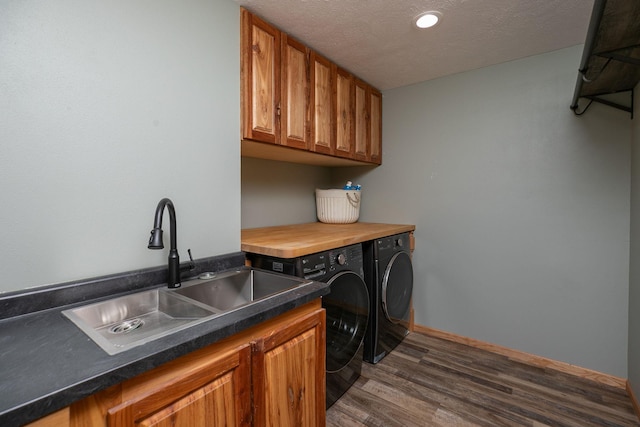 laundry room featuring a textured ceiling, separate washer and dryer, dark wood-style flooring, a sink, and cabinet space