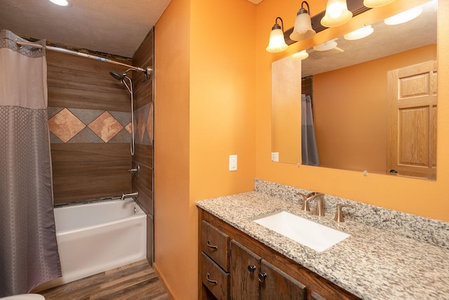 full bath featuring a textured ceiling, shower / bath combo, wood finished floors, and vanity