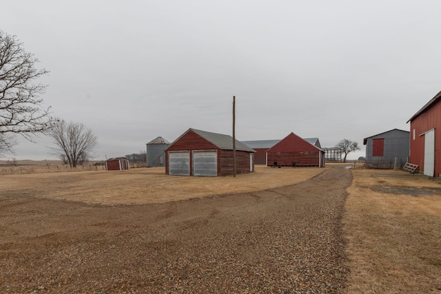 view of yard with dirt driveway, an outbuilding, a detached garage, and an outdoor structure