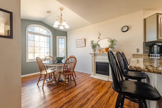 dining area with lofted ceiling, an inviting chandelier, baseboards, and dark wood finished floors