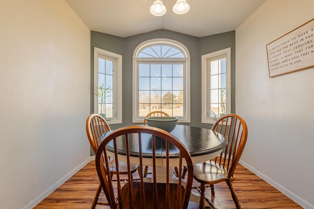 dining space with lofted ceiling, baseboards, and wood finished floors