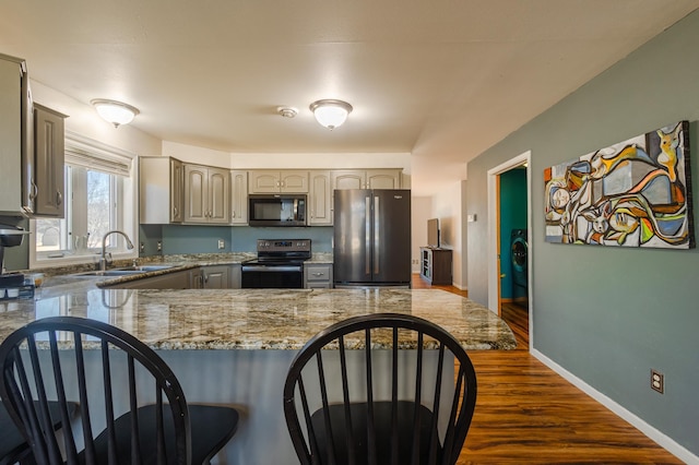 kitchen featuring a kitchen bar, baseboards, stainless steel appliances, and a sink