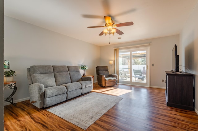 living area with a ceiling fan, dark wood finished floors, and baseboards